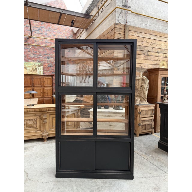 This antique display cabinet with a black patina has been fully restored. It consists of an upper section featuring...