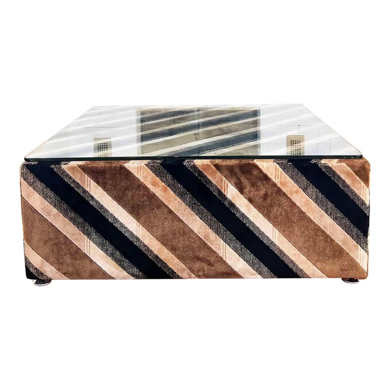 A rectangular coffee table with a glass top and a striped fabric base in shades of brown, black, and beige.