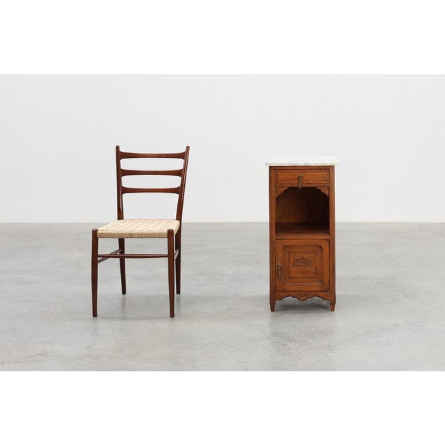 A refined French Art Deco nightstand from the 1920s, crafted in warm oak and crowned with a beautifully veined Carrara...