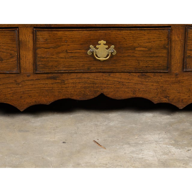 An English Georgian period small oak buffet from the 18th century, with double doors, drawers, arching motifs and brass...