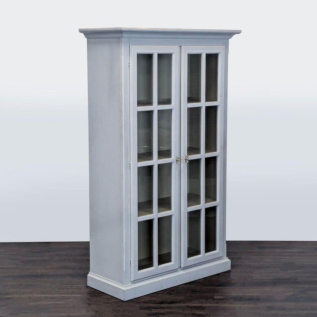 This Crate & Barrel bookshelf features a clean, modern design with glass double doors and a soft gray finish. It includes...