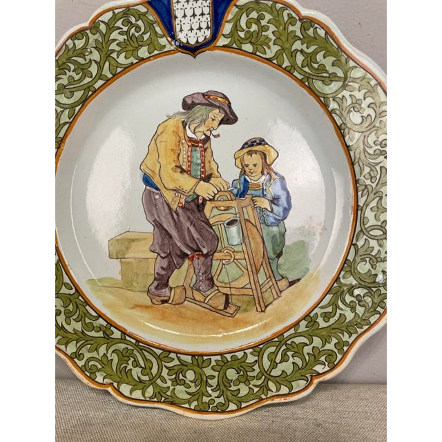 A good 19th century French Porquier Beau Quimper Plate with a green border depicting a man with a your child sharpening a...
