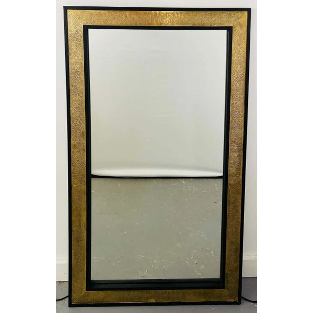 A pair of glamorous Hollywood Regency style brass over ebonized wood Moroccan pier, wall or console mirrors. The...