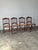 A set of four dining chairs with turned spindle backs, shaped crest rails, and cane seats set on gently splayed saber...