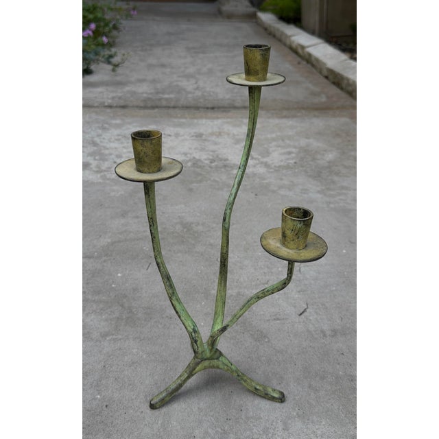 A beautifully aged vintage three-arm candelabra featuring an elegant, organic silhouette and rich verdigris patina. The...
