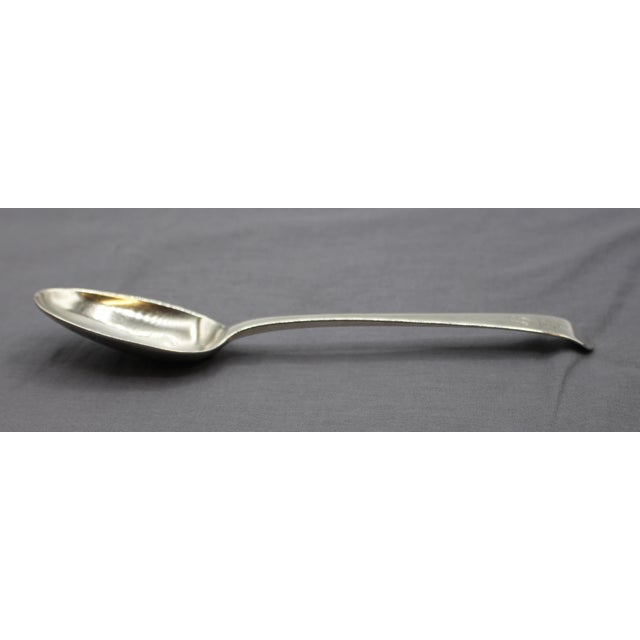 George II sterling silver tablespoon, London, 1749. Old English pattern. With a family crest of a figure with dexter hand...