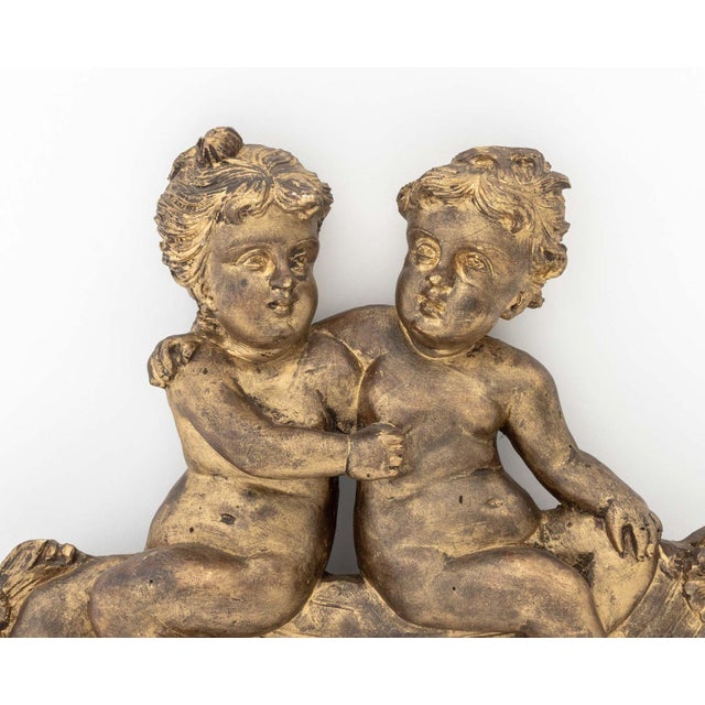 Belle Epoque Style Pair of Cherubs Gilt Plaster Applique, the two nude figures seated atop drapery and flowers. 14" H x...
