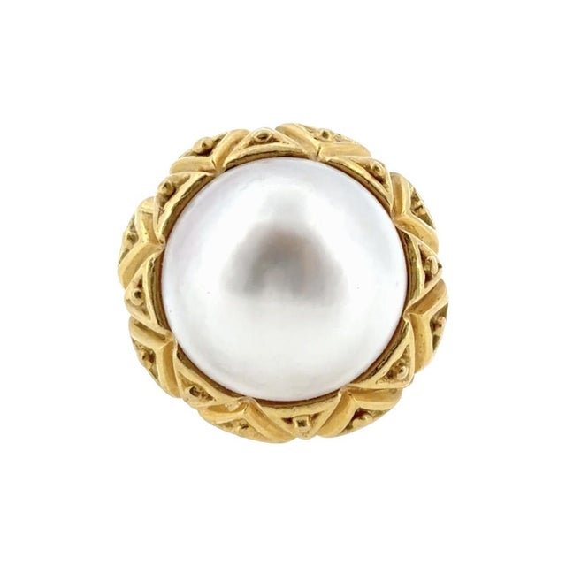 Circa 1980's Tiffany & Co. 18K gold ring. The centerpiece is a mabe white South Sea pearl set in an intricate yellow gold...