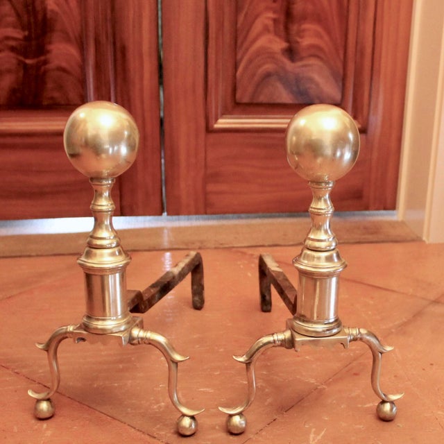 A handsome pair of mid-sized andirons with large ball tops atop turned columnar shafts, resting on outswept spurred legs...