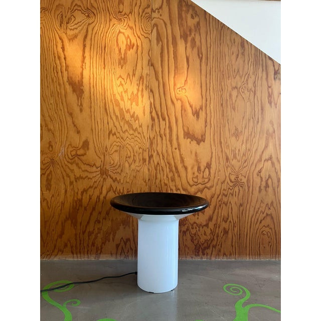 Milky glass and black metal table lamp, circa 1970. This table lamp features a milky glass base that gives the structure a...