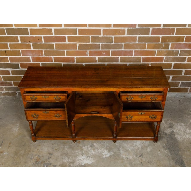 An English oak dresser base from the 19th century with marquetry, banding, doors and drawers. This 19th-century English...
