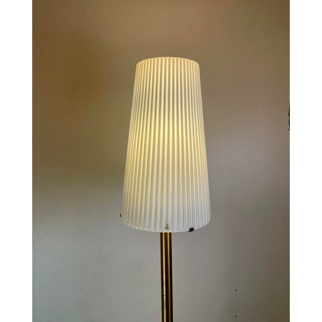 Beautifully made floor lamp made of a black round foot with a thick brass leg and a stunning fluted murano glass white...
