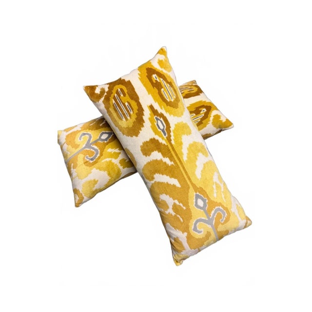 These decorative throw pillows feature a vibrant yellow ikat pattern on one side and a solid mustard yellow velvet fabric...