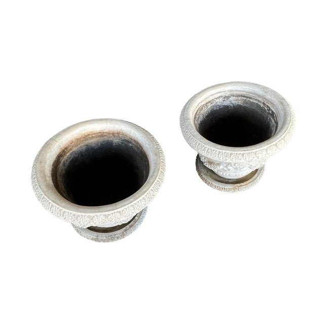 each boldy-scaled planter of conical form with rolled lip adorned with acanthus leaf motifs above a tapering body...