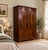 An Edwardian mahogany double wardrobe featuring striking oval flame-mahogany panels and a moulded cornice. The spacious...