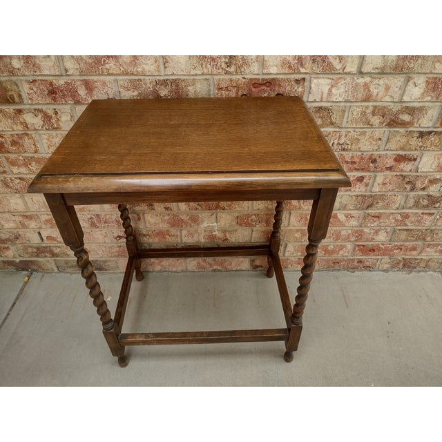 Charming vintage oak side table featuring classic barley-twist legs, a richly toned rectangular wood top, and traditional...