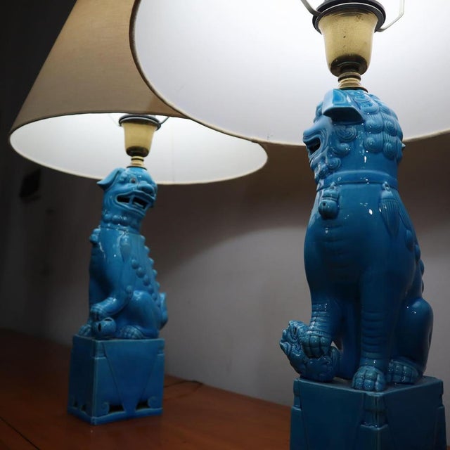 Elegant pair of vintage Chinese Foo Dog lamps, crafted from bright blue ceramic. These decorative lamps are inspired by...