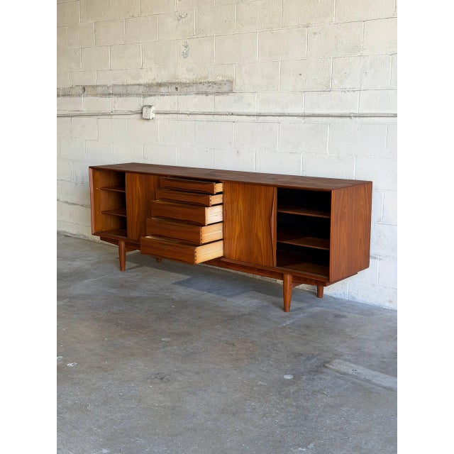 This expansive storage unit features a balanced layout with a central bank of five drawers flanked by two sets of sliding...
