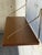 Vintage Mid-Century Modern floating teak wall shelf featuring a warm wood finish and elegant brass-toned metal brackets....