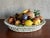 Mid 20th Century Italian Majolica ceramic fruit basket or bowl featuring apples, oranges, a plum, a pineapple, a lemon,...