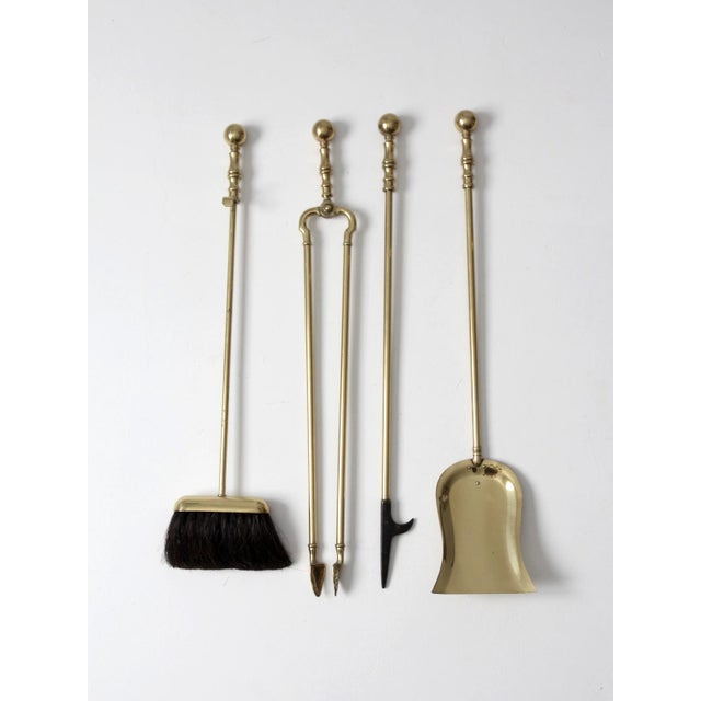 A vintage brass fireplace tool set with a classic Colonial Revival presence, defined by turned handles, rounded finials,...