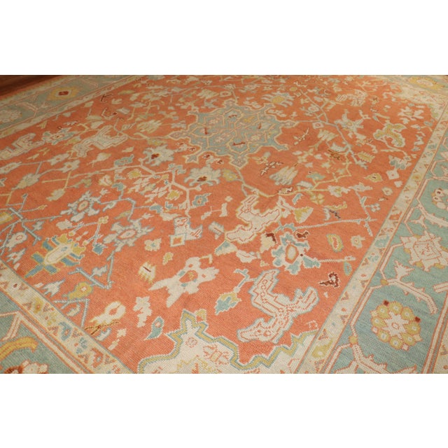 An early 20th-century orange field antique Oushak Measures: 11'7” x 15'6”.