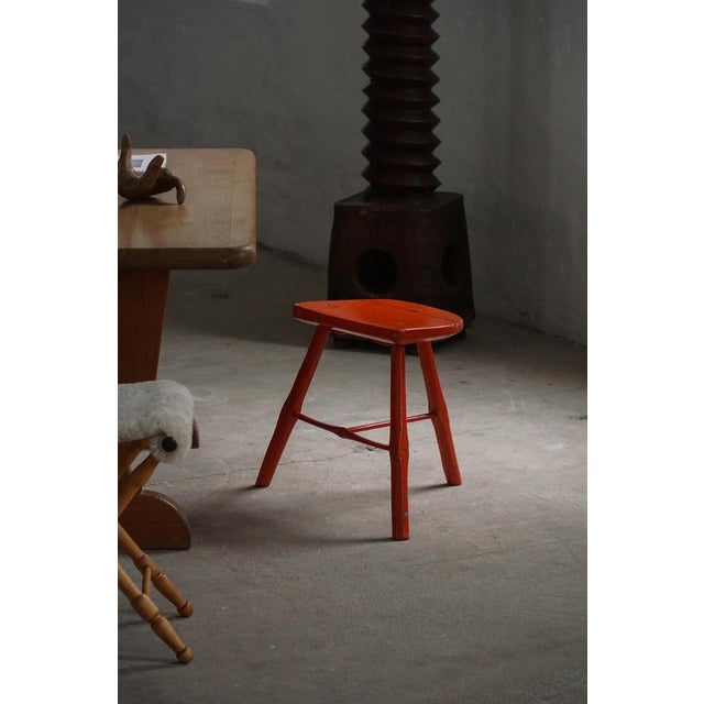 A charming pair of vintage wooden stools, featuring three splayed legs connected by crossbars for added stability. The...