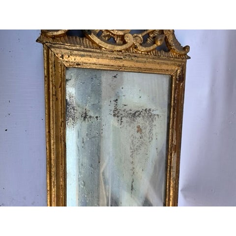 A single antique carved and gilt wood wall mirror featuring carved decoration including scrolls, foliage, flowers, and an...