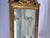A single antique carved and gilt wood wall mirror featuring carved decoration including scrolls, foliage, flowers, and an...