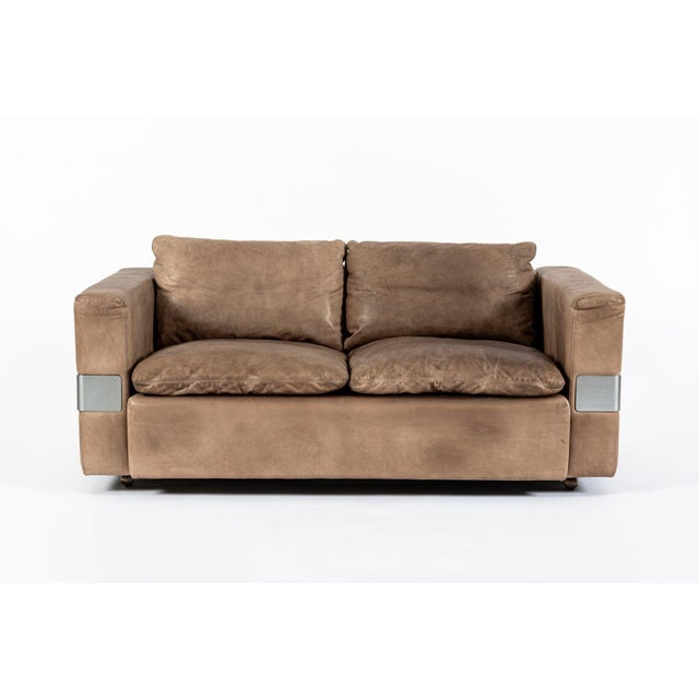 This vintage mid century German modern brown leather two-seat loveseat sofa in the style of Robert Haussmann for Hans...