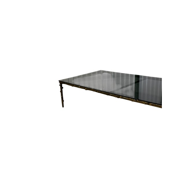 This coffee table features a bronze base designed in the Hollywood Regency style, characterised by its bamboo-inspired...