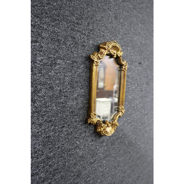 Italian Syroco gilt wall mirror featuring an ornate Rococo-style frame with a prominent shell-form crest, scrolling...