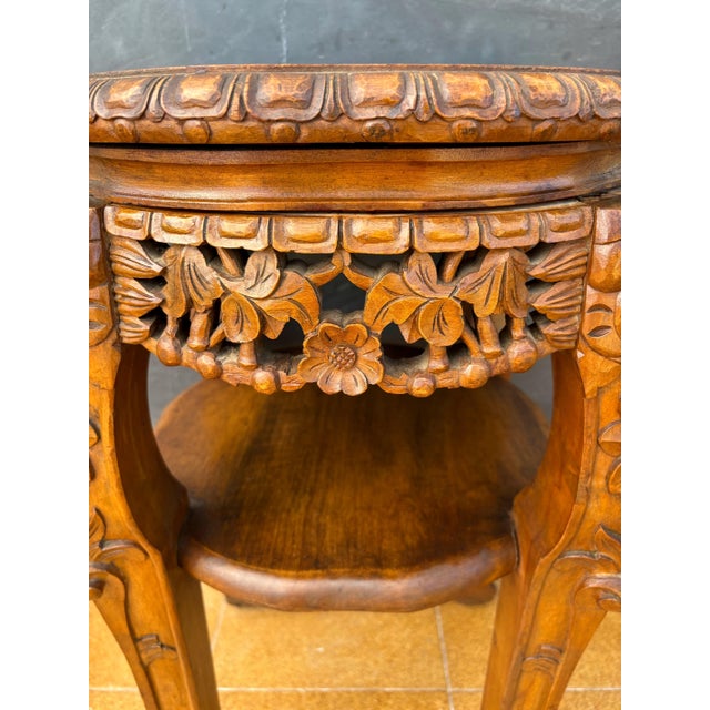 Chinese carved hardwood accent table, mid-20th century. The circular top rests above an intricately carved apron featuring...