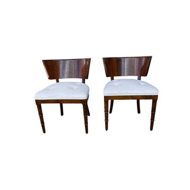 The two chairs are attributed to Emilio Lancia. They have a wide, curved back, visible rings on the front legs, and a...