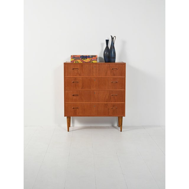 Teak chest of drawers with four drawers and recessed handles, a simple structure on tapered turned legs. Elegant...