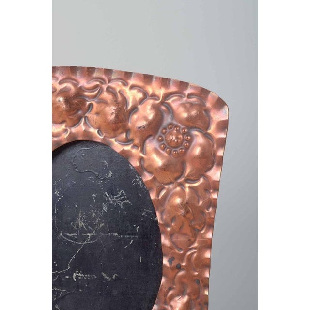 Two decorative picture frames in embossed copper with floral motifs and oval openings. Reverse with a support stand for...
