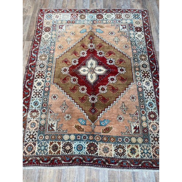A lovely vintage Oushak rug. This rug offers an earth tones palette with shades of red, orange, blue, and white.