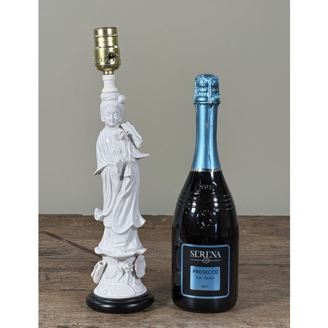 Vintage Japanese Blanc de Chine porcelain table lamp depicting Guanyin in flowing robes, mounted on a black wooden base...