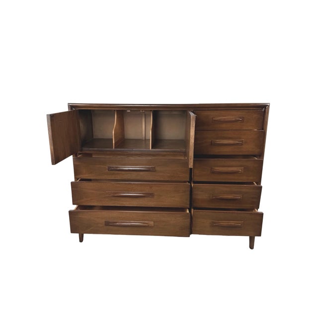 This Broyhill Emphasis gentleman’s chest combines an asymmetrical storage arrangement with sculpted details that give the...