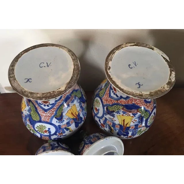 Pair covered Delft urns measuring just over 12" tall. Polychrome decoration mimics Kangxi porcelain of the period. Good...