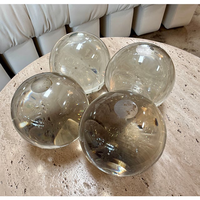 Decorative set of four handblown glass spheres in clear and smoky-gray tones. Each piece features subtle variations,...