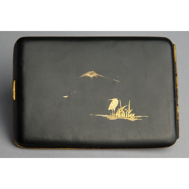 A Japanese Komai style damascene cigarette case with richly detailed gold inlay on blackened steel, featuring a different...