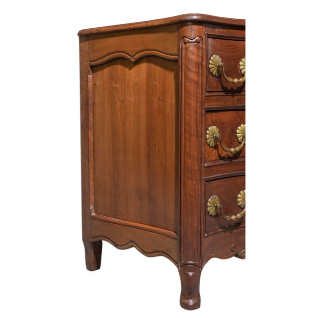 A beautifully contoured Louis XV style walnut commode featuring a serpentine front, scalloped apron, and finely carved...