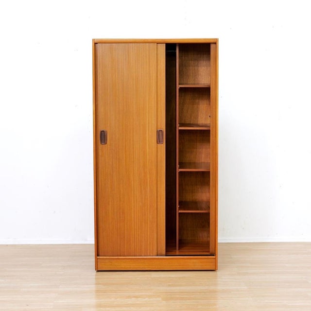This vintage mid-century armoire was produced by Austinsuite Furniture during the 1960s. Made from teak the two front...
