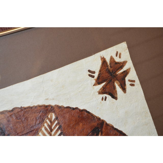 This is a framed piece of Tapa art. Simple metal frame, brushed copper/bronze color, & behind glass. The back has a...