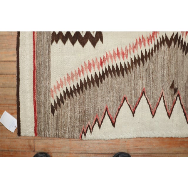 An early 20th-century high-decorative American Navajo rug featuring a pattern resembling a sharks tooth in gray, ivory and...