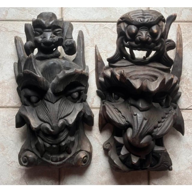 vintage or antique hand-carved Asian wooden guardian or demon masks, often featuring stacked or multi-tiered faces with...
