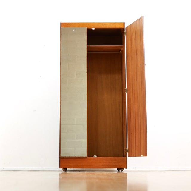 This vintage mid-century armoire was produced by Elliots of Newbury during the 1960s. Made from teak the front hinged door...