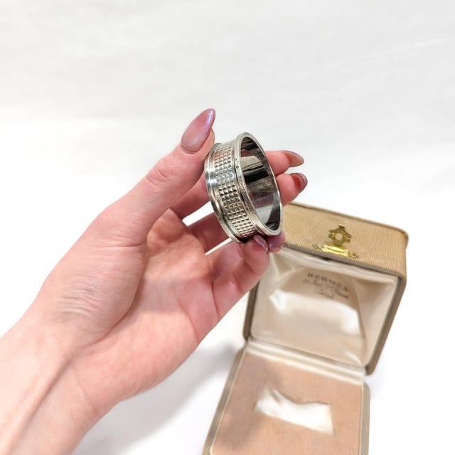 A fine antique signed napkin ring. By Hermès. In sterling silver. With a hobnail pattern with plain borders to either...