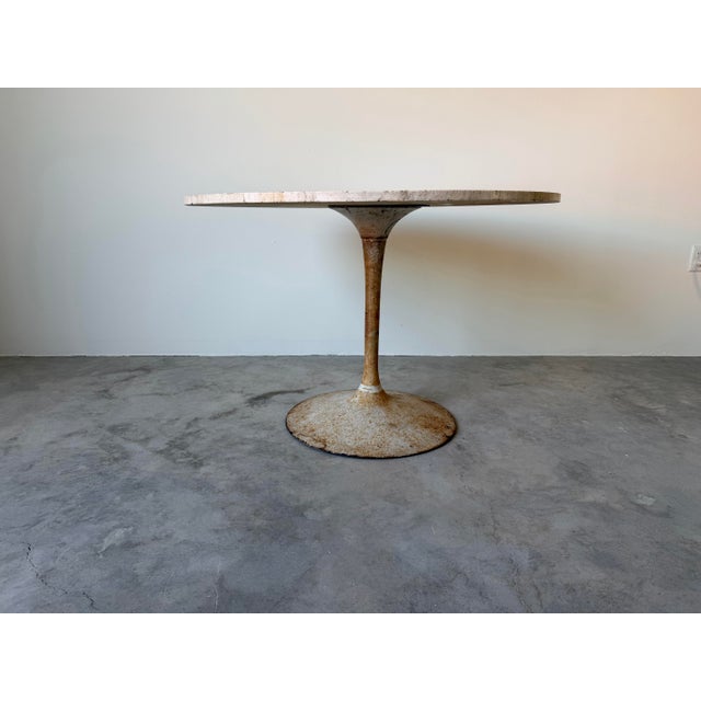 A classic and sculptural vintage dining table featuring an elegant tulip-style metal base paired with a beautiful round...